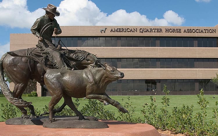 Statue of man on horse lassoing a cow